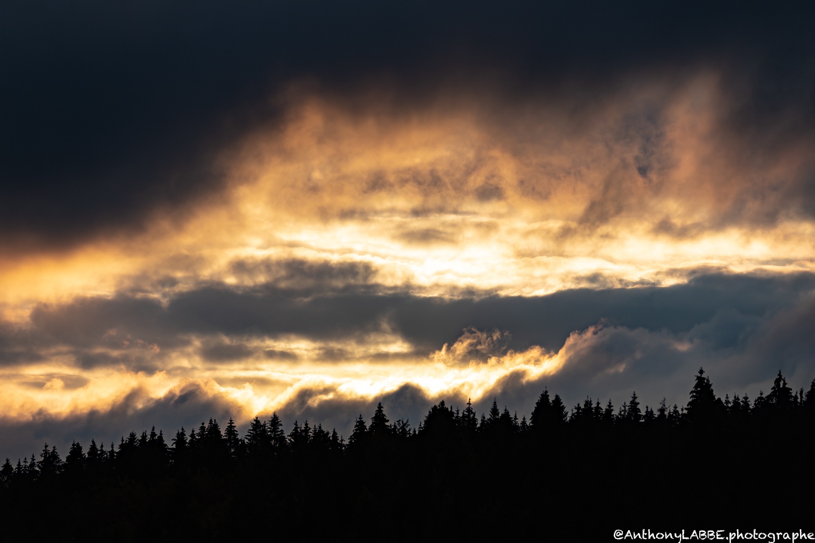 couche de soleil dans les nuages au dessus de la foret Jura France